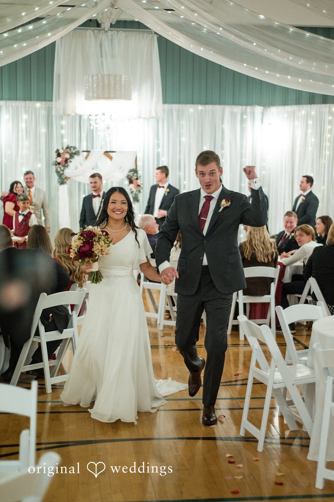 Wide portrait of the bride and groom walking toward the reception