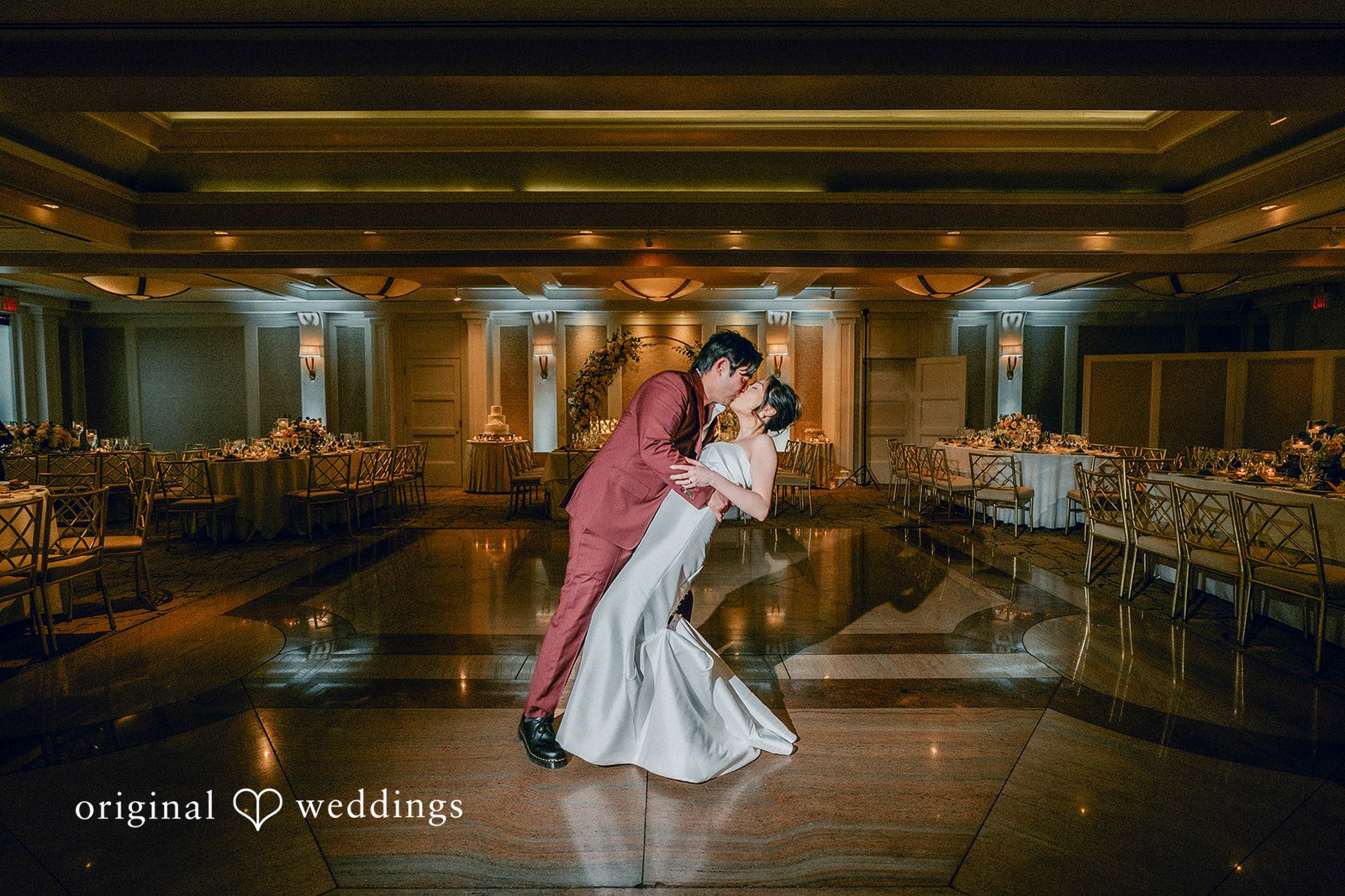 The couple takes a romantic kiss at their wedding reception hall
