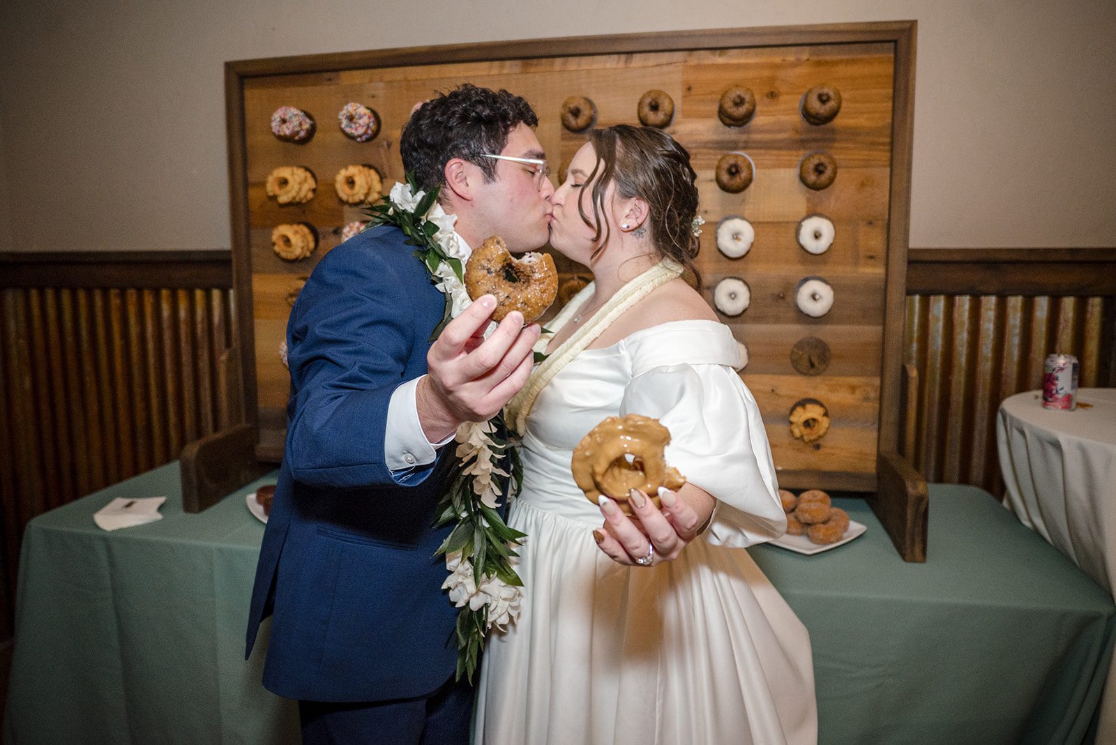 Tiare + Jeremy Bride and groom kissing while holding donuts at Gorge Crest Vineyards