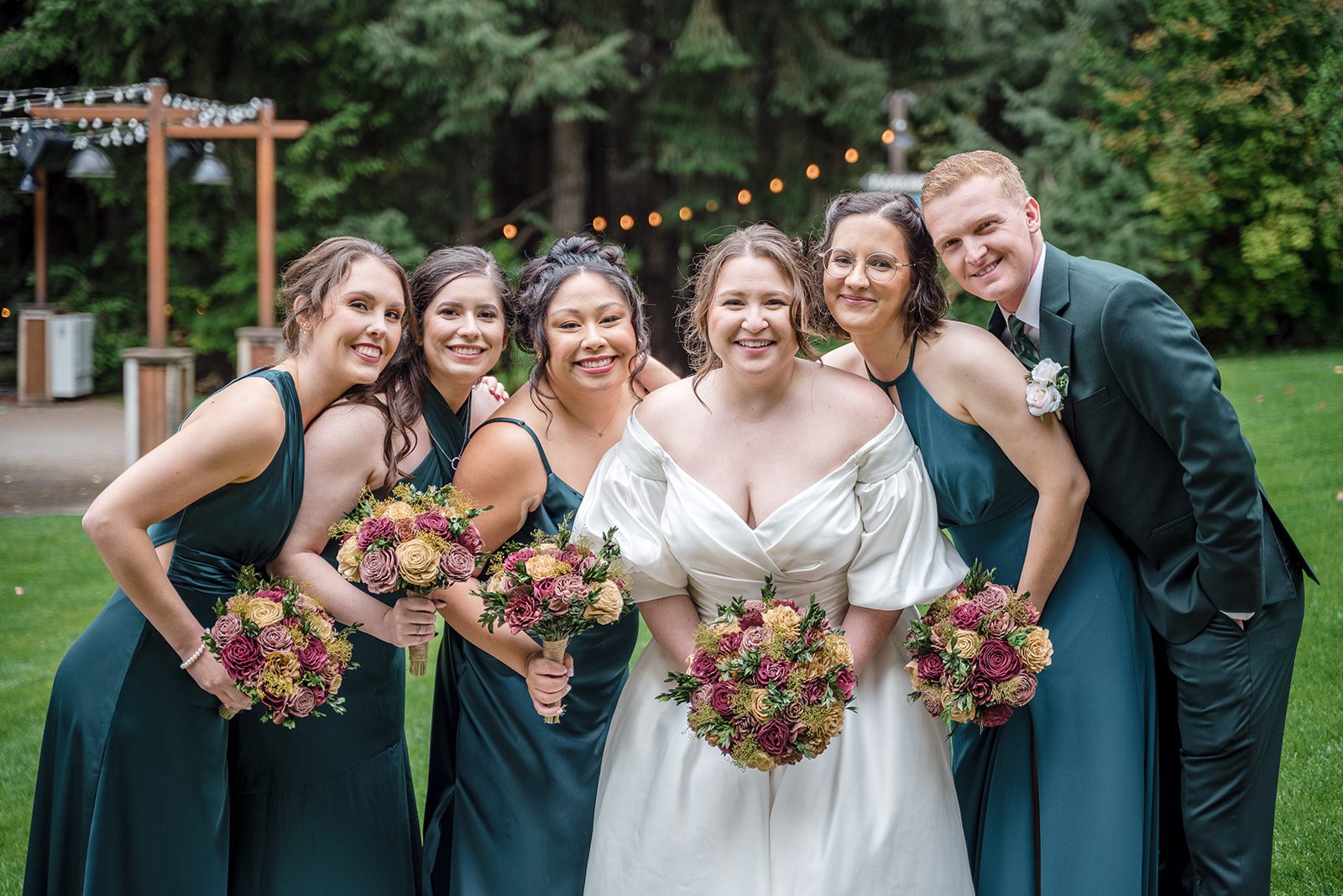 Tiare + Jeremy Outdoor wedding celebration photo of bride surrounded by bridesmaids and a groomsman in a garden