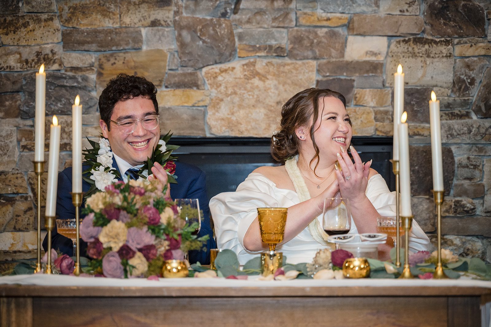 Tiare + Jeremy Romantic wedding reception picture featuring newlyweds laughing together beside candles and floral arrangements