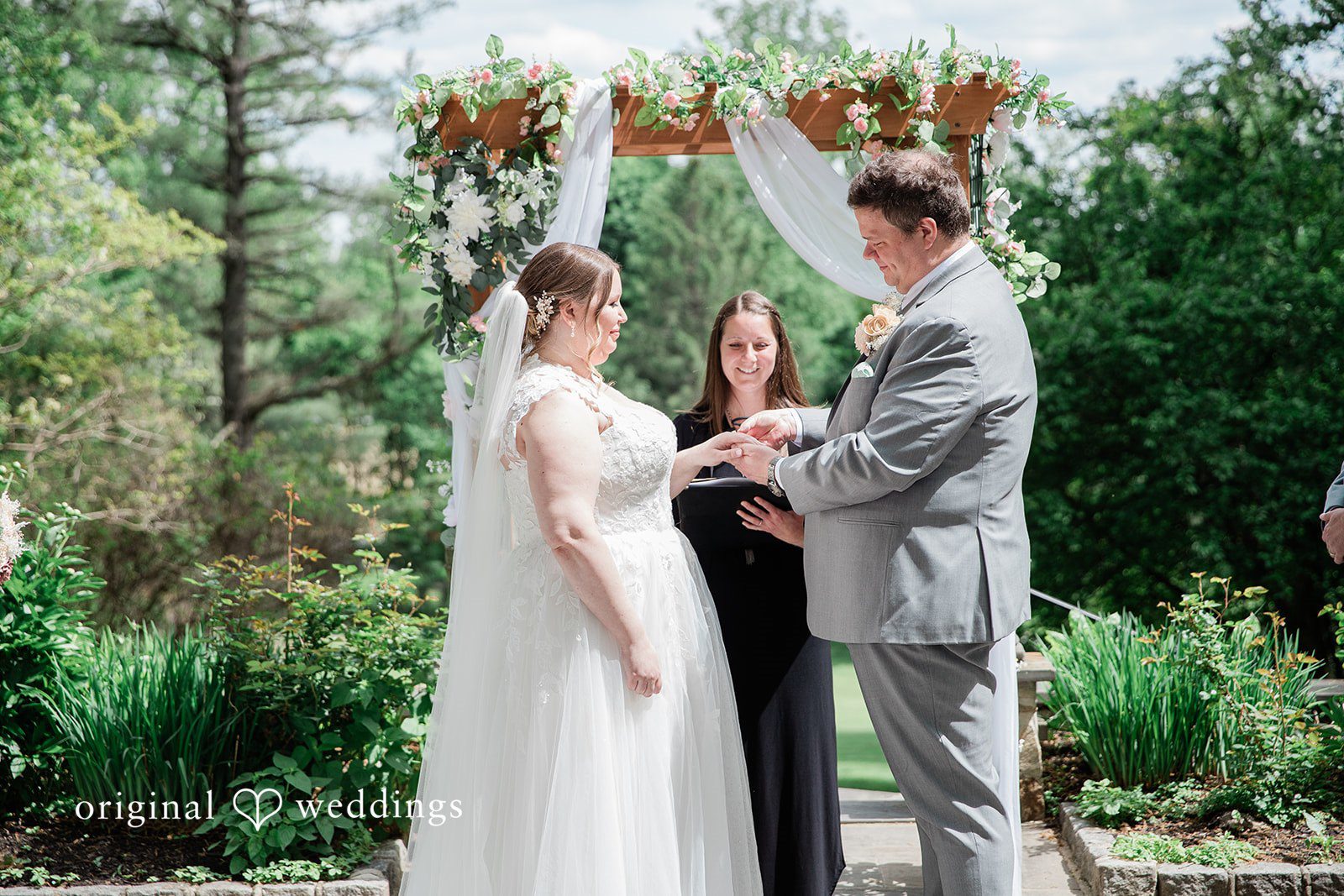 Nicole + Greg The groom puts the ring on the bride’s finger