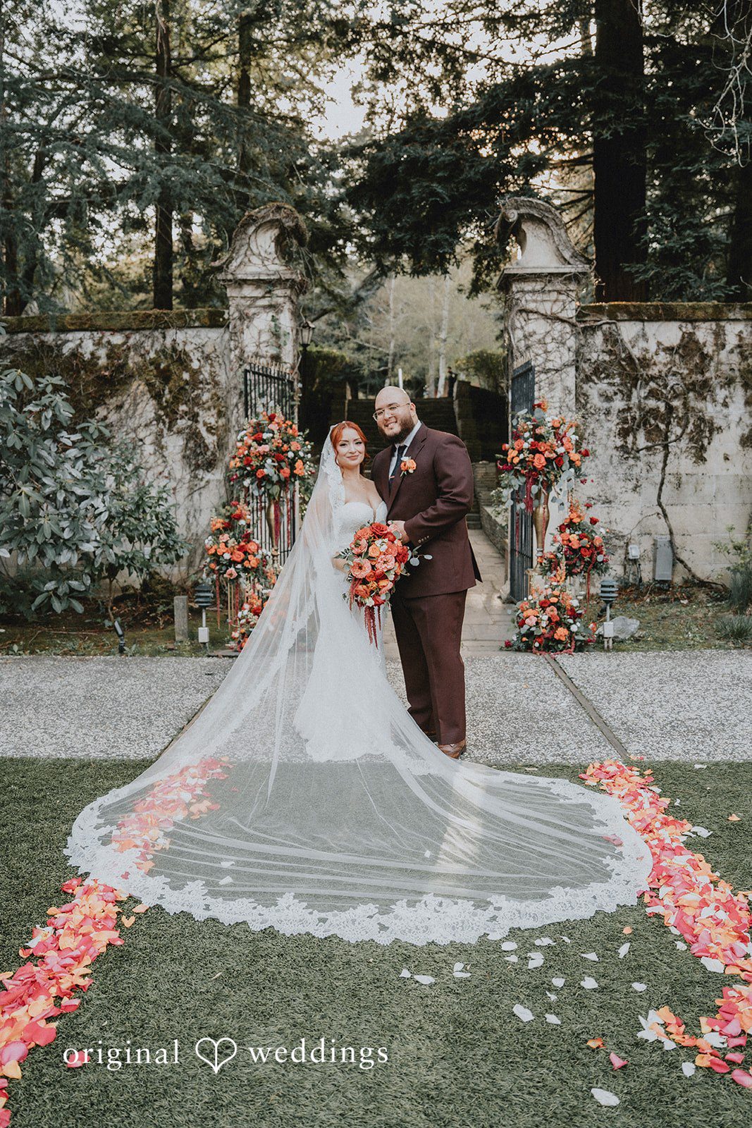 Bride and groom pose in a garden with floral arrangements