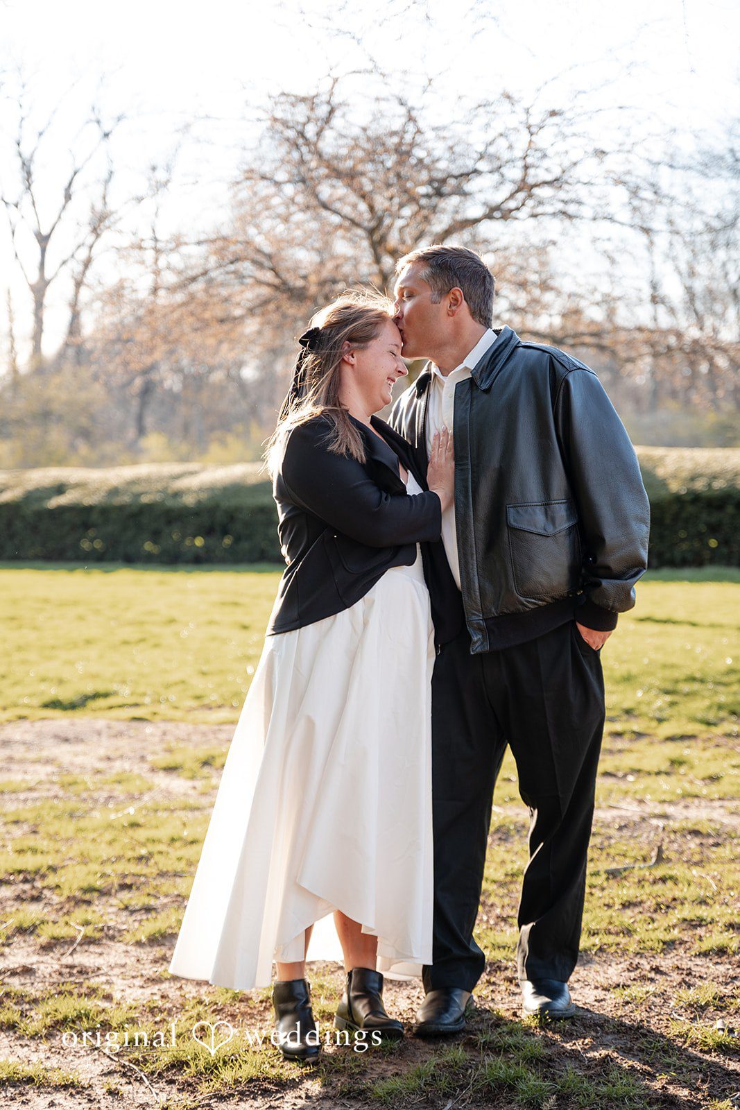 Romantic groom kissing bride on forehead during engagement session