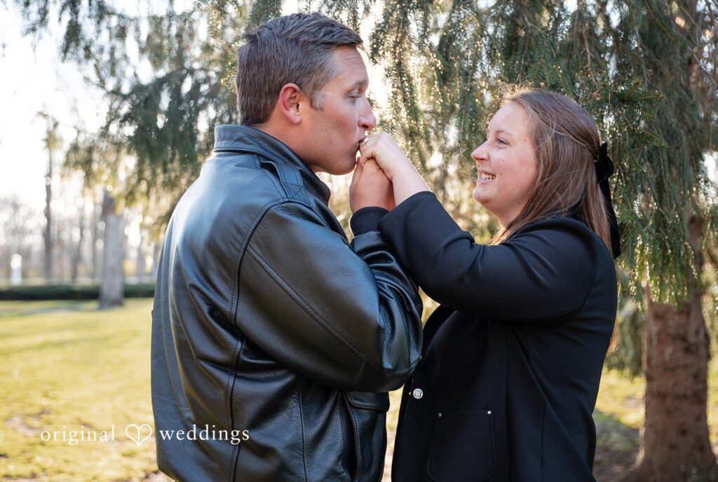Engagement photography services by Original Weddings capturing groom kissing bride’s hand at Holcomb Gardens