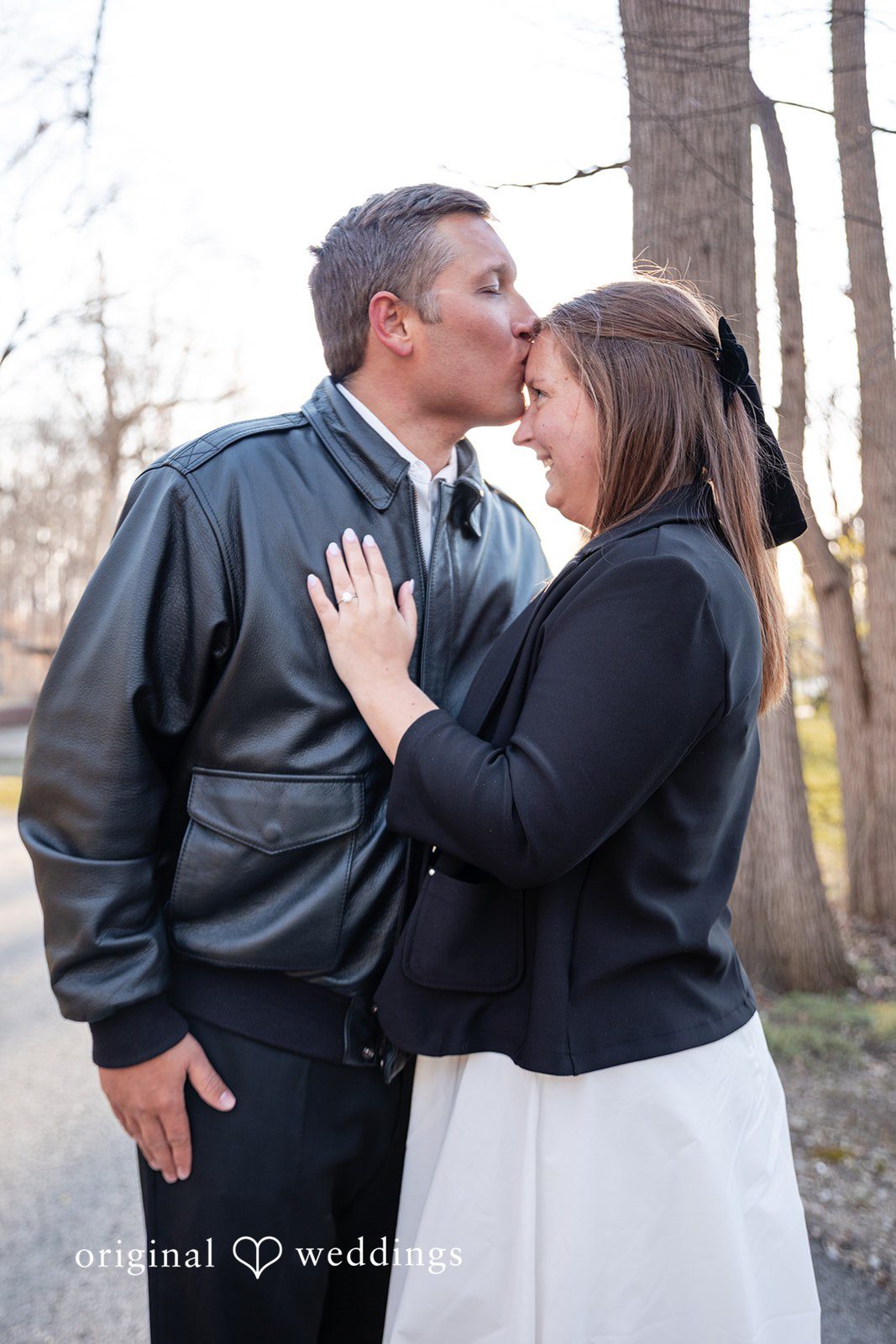 Elegant couple pose with groom kissing bride’s forehead