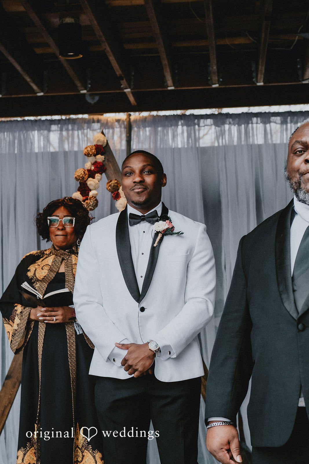 The groom in a white tuxedo jacket standing with his groomsmen.