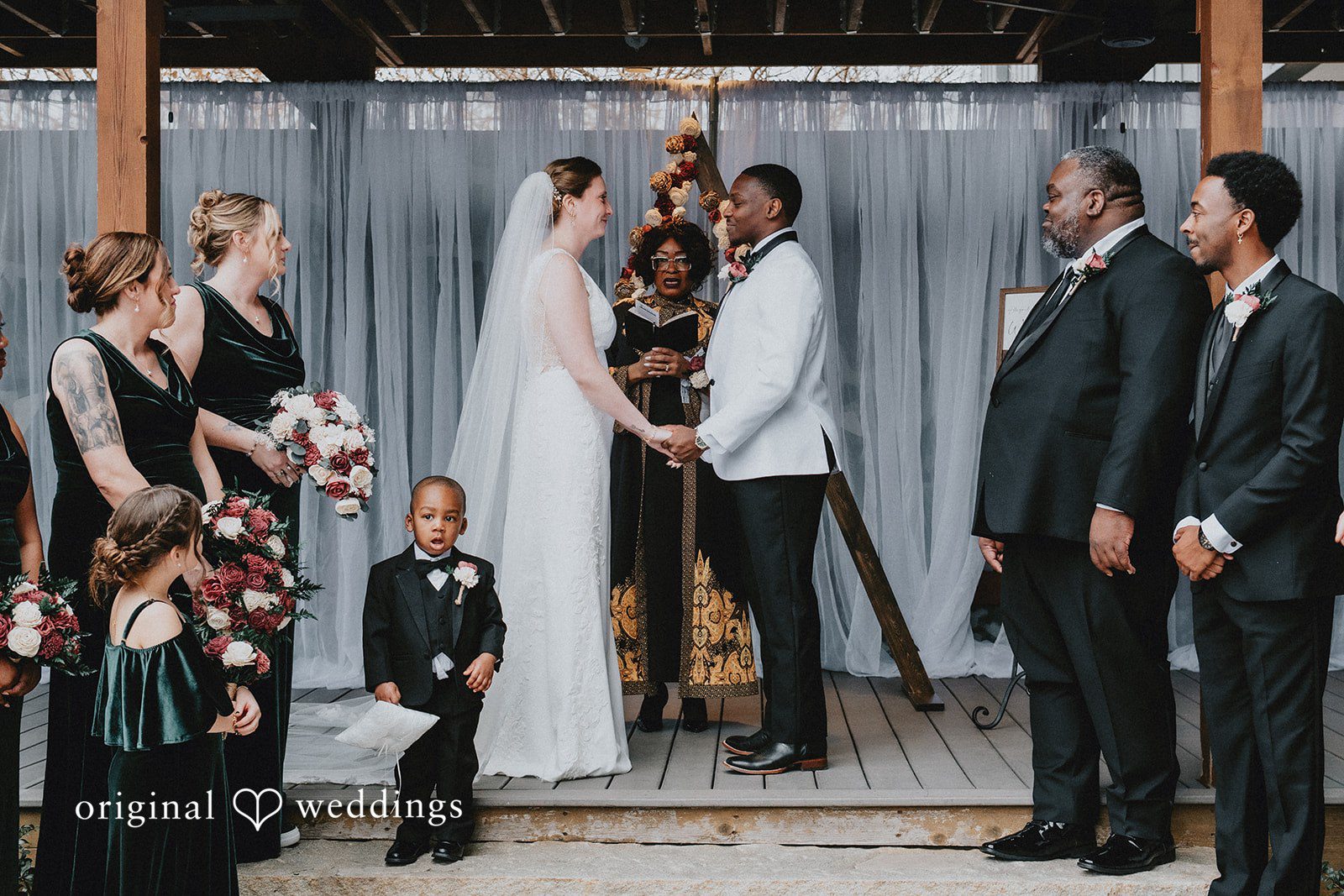 A wide shot of the wedding ceremony taking place on a raised wooden stage.