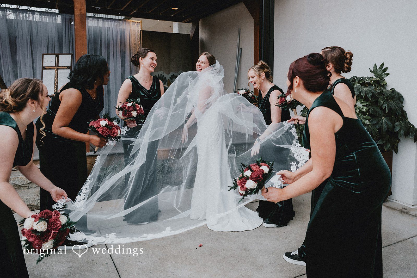 A bride and bridesmaid in a black dress share a moment during the wedding preparations.