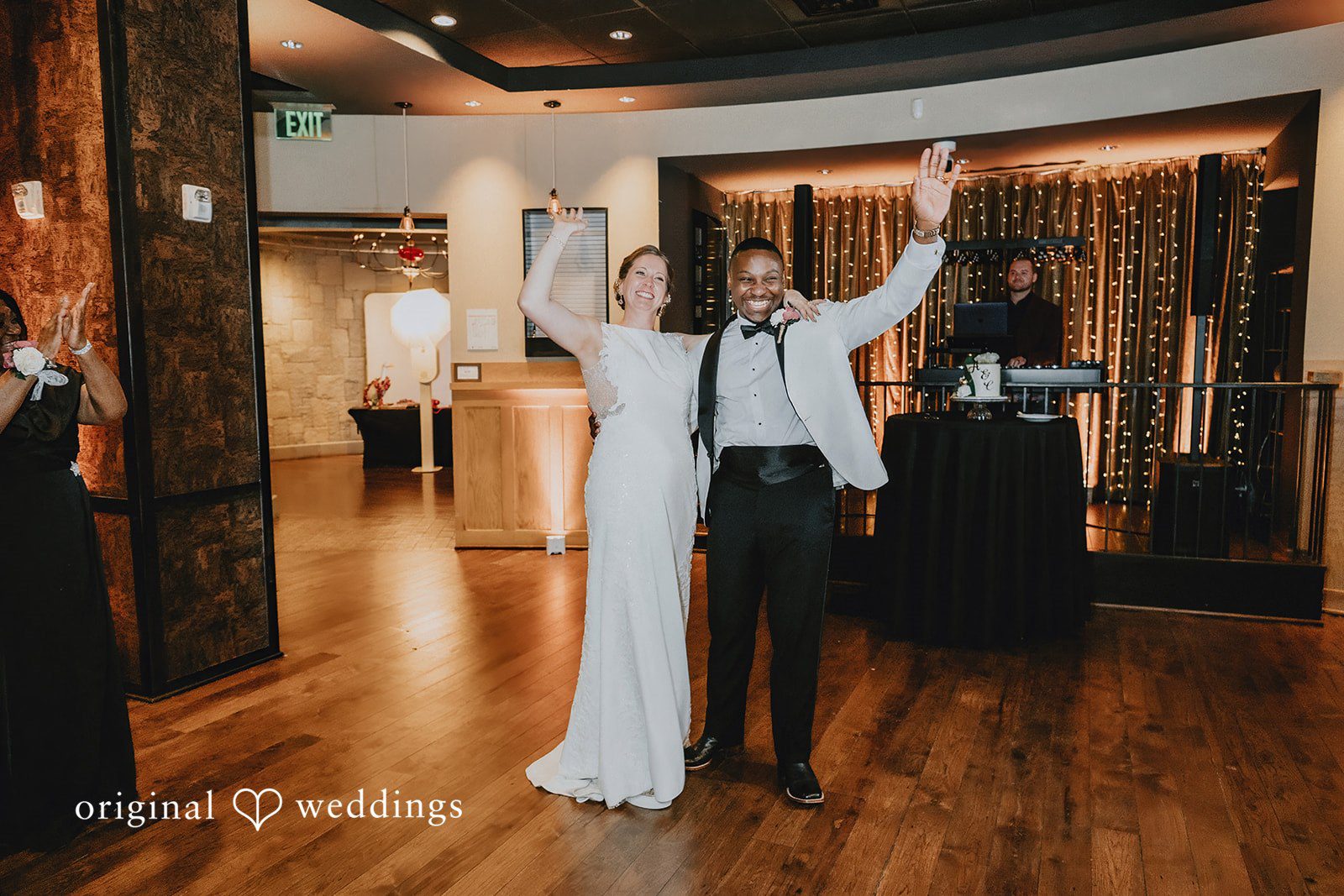 The newlyweds walking into their reception with their hands raised in celebration.