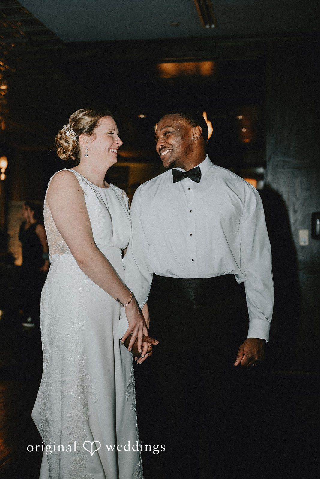 A candid shot of the couple holding hands and smiling at each other during the reception.