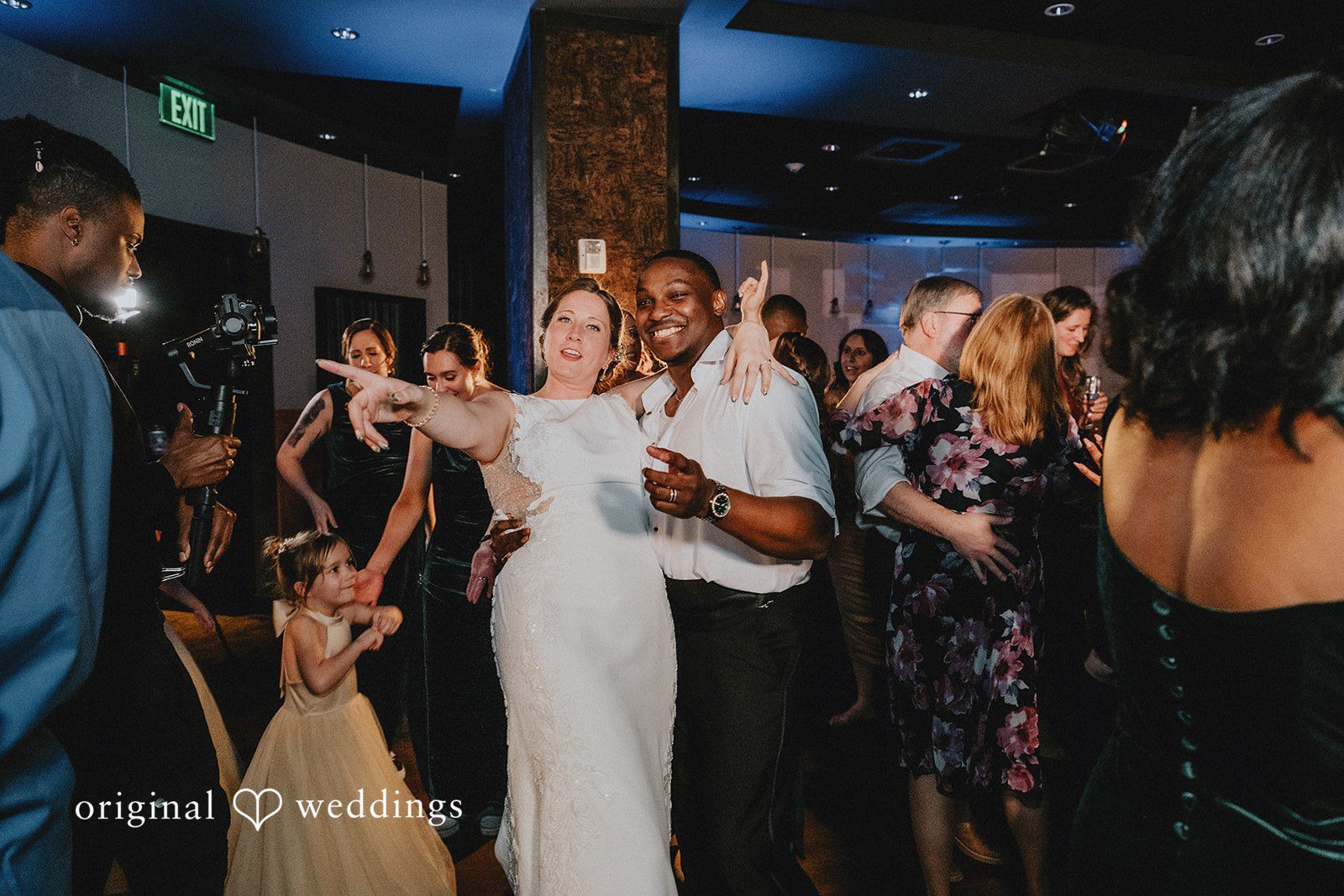 The bride dancing and laughing with guests on a crowded dance floor.
