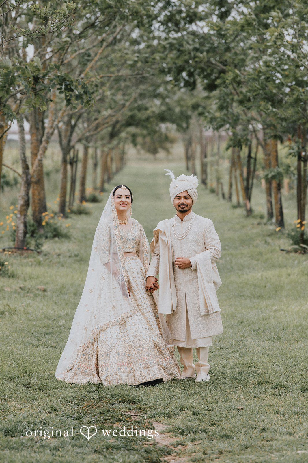 Chandrakant + Sumbul Wide portrait of the couple walking through the garden together