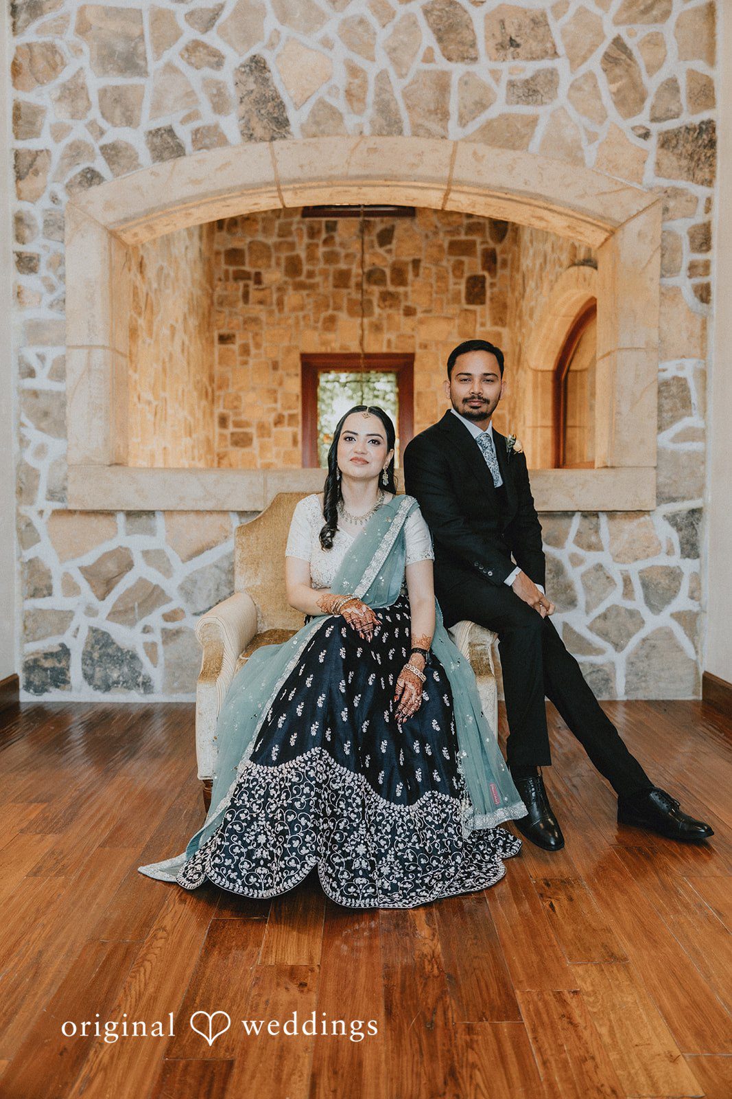 Chandrakant + Sumbul Bride seated while the groom stands beside her during the reception