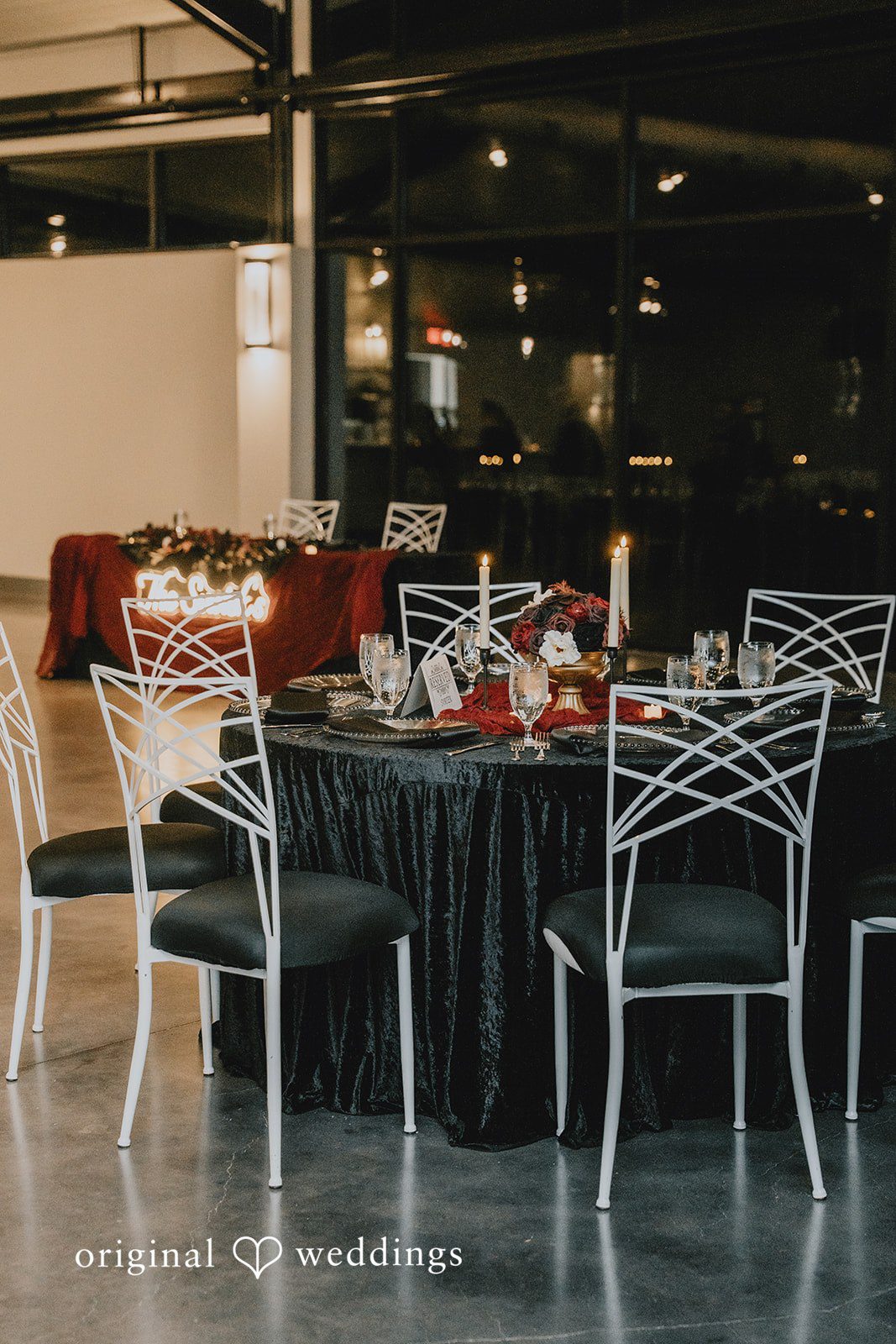Reception table with black linens and red flowers.