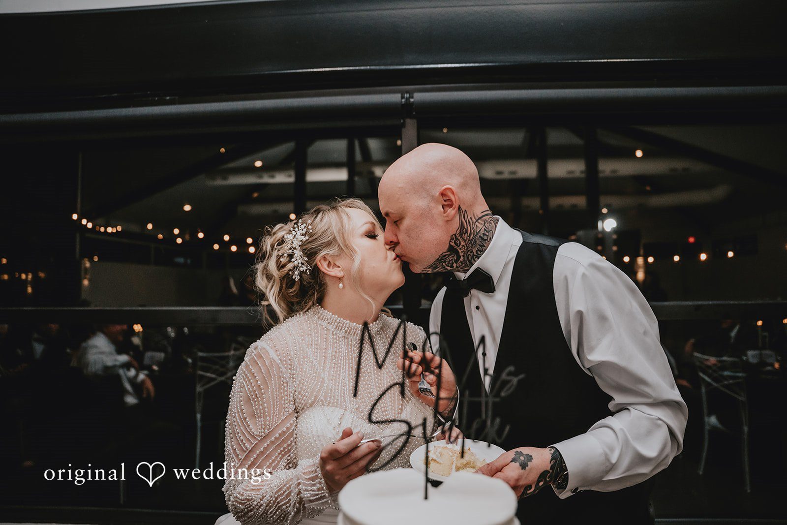 Groom kissing bride while holding a cake plate.