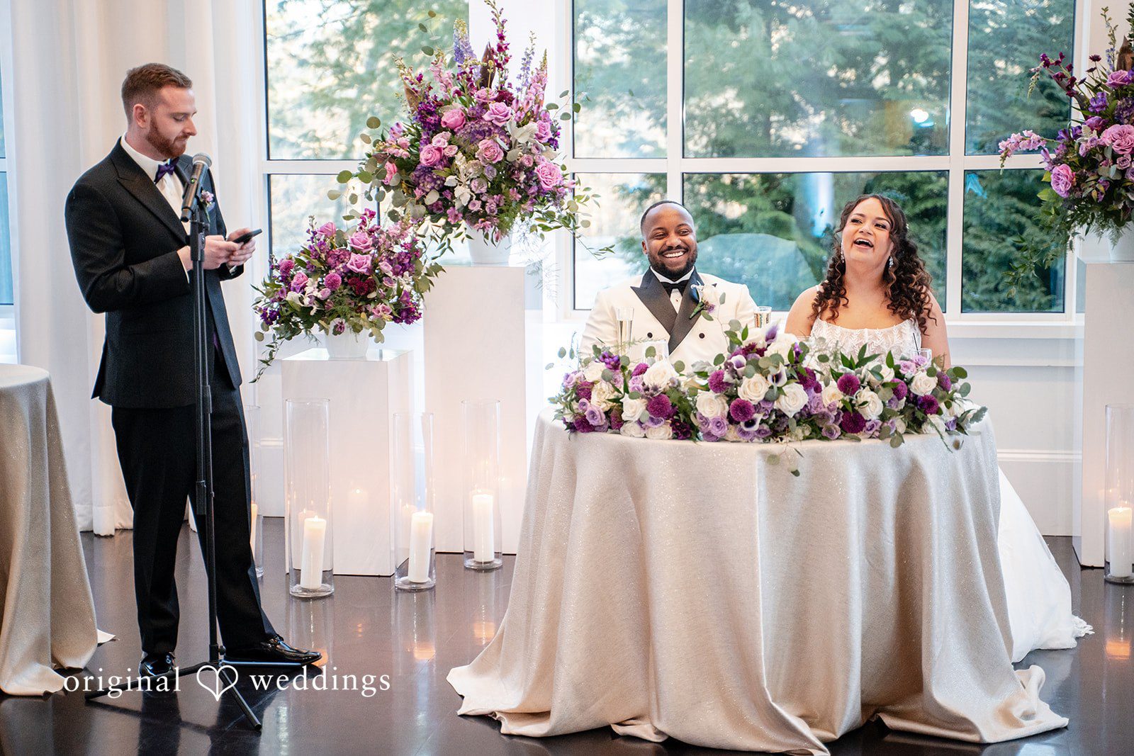 Wedding reception speeches with couple smiling at their table