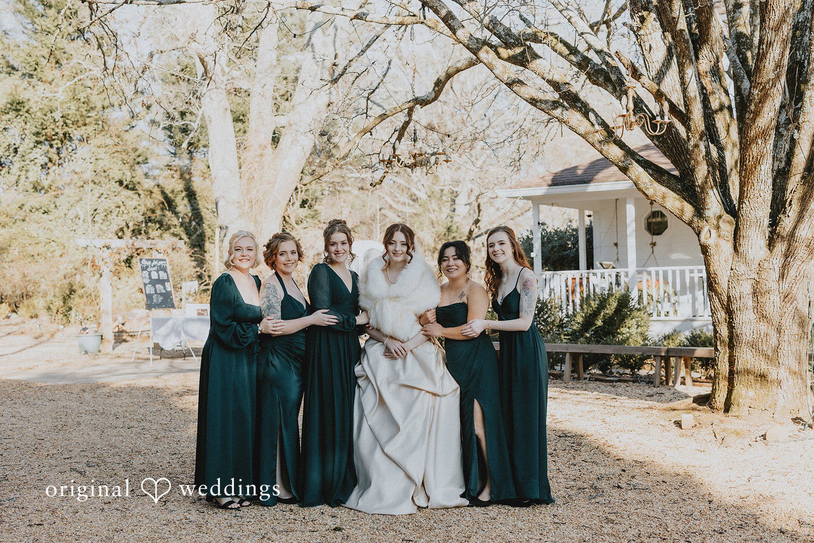 Ayana + Gabriel A bride posing with her bridesmaids dressed in dark forest green gowns.