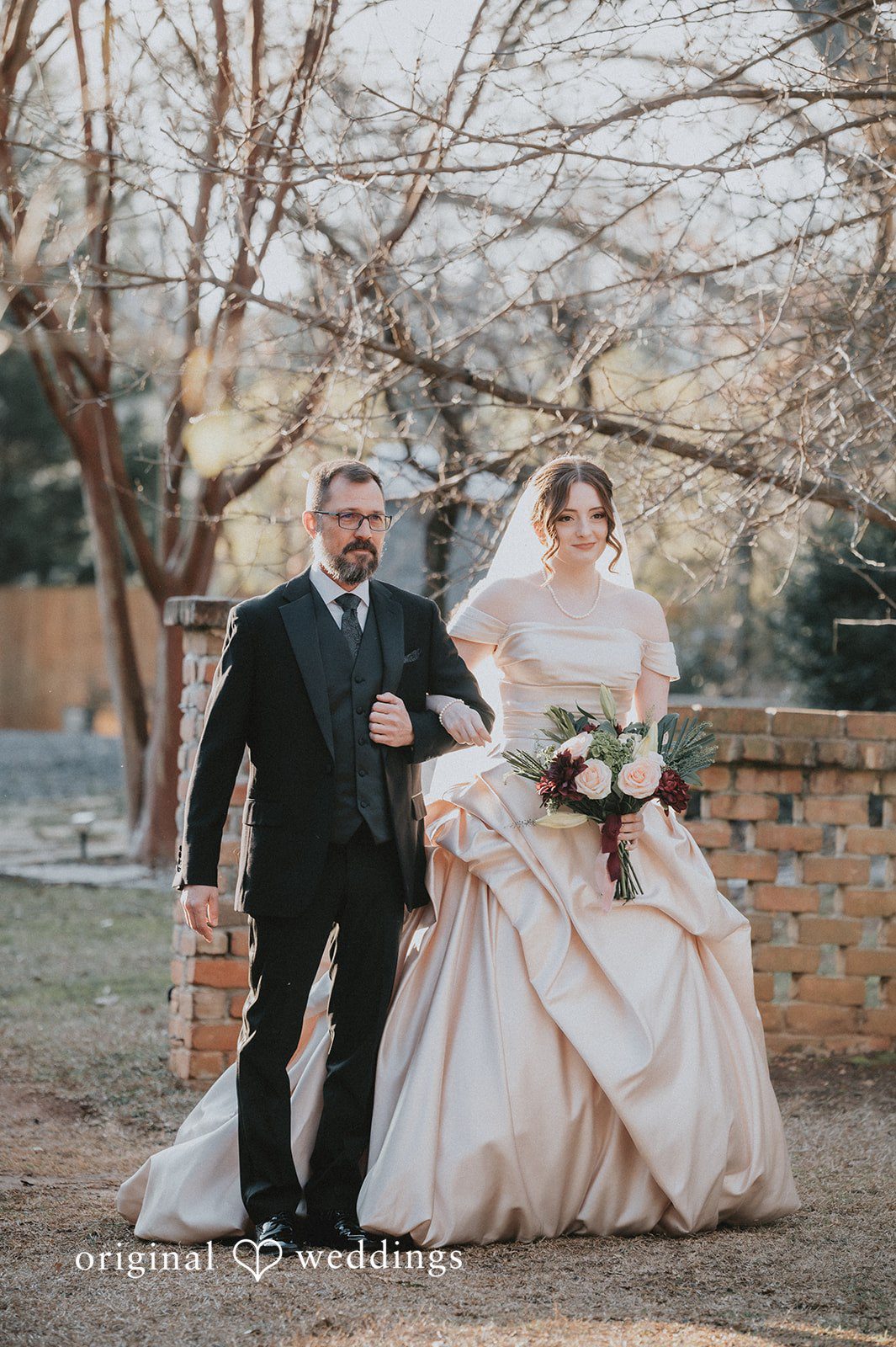 Ayana + Gabriel A bride walking arm-in-arm down a path with a man in a black suit.