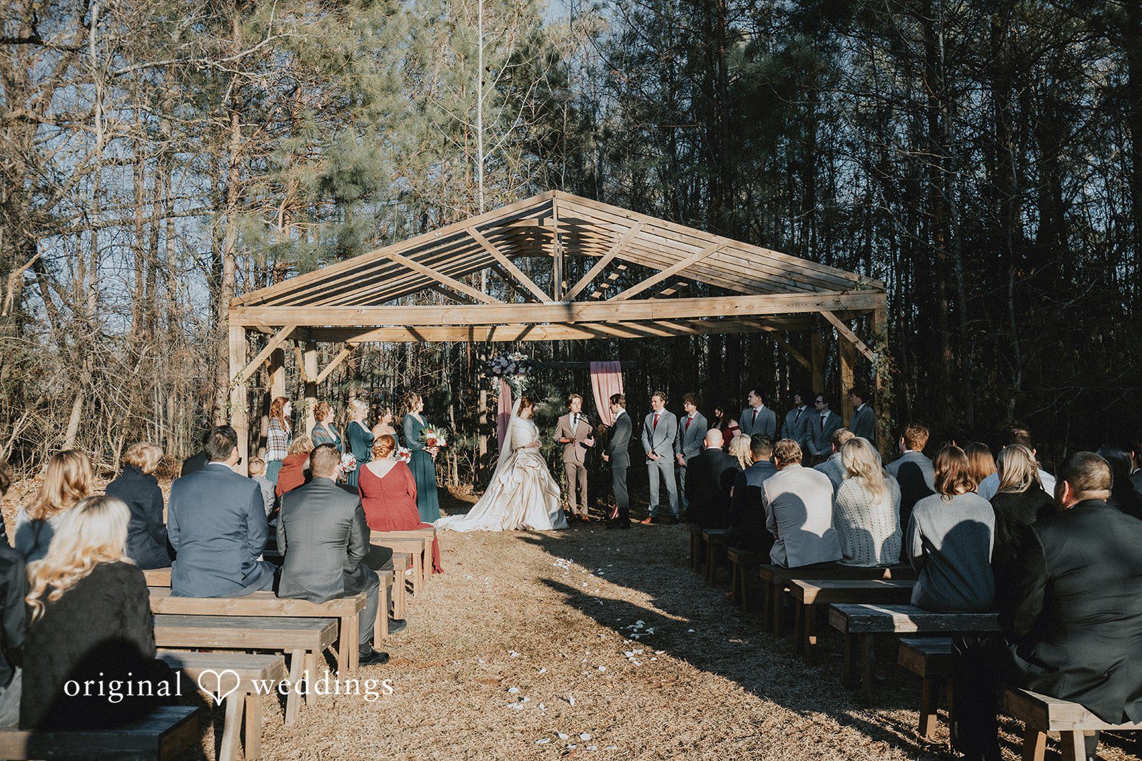 Ayana + Gabriel Seated guests facing a wooden altar structure during a wedding ceremony.