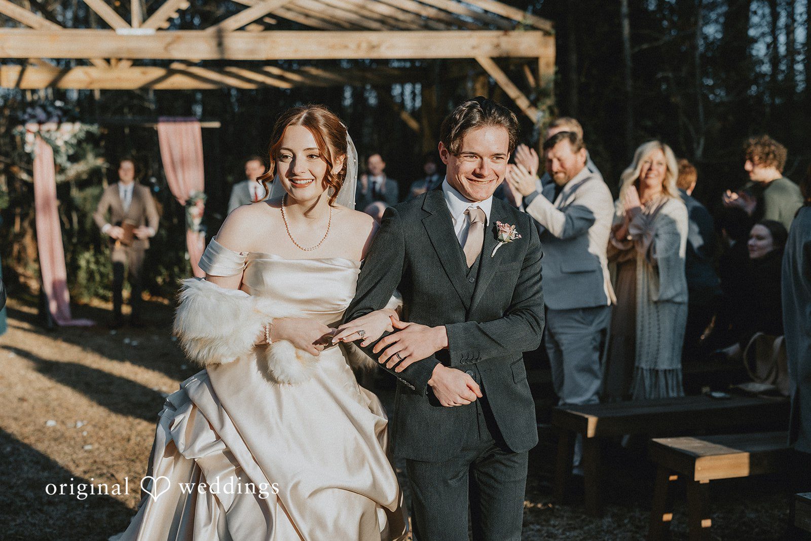 Ayana + Gabriel Newlyweds smiling while walking down the aisle together as guests look on.