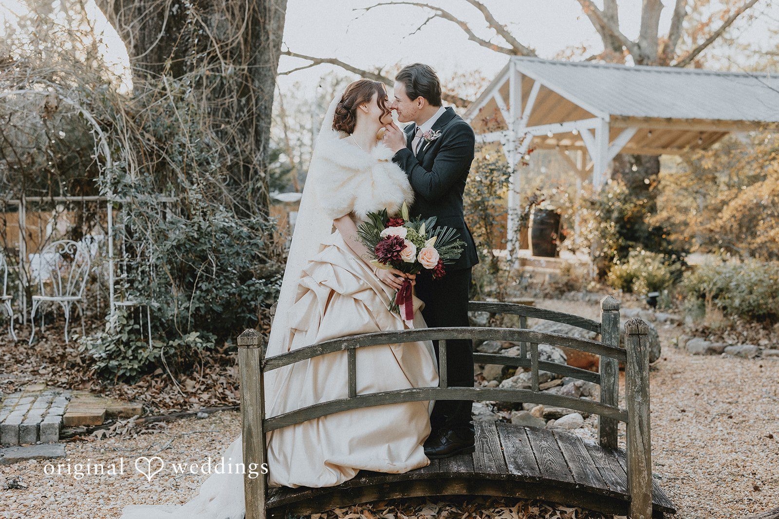 Ayana + Gabriel Bride and groom kissing while standing on a decorative wooden bridge.