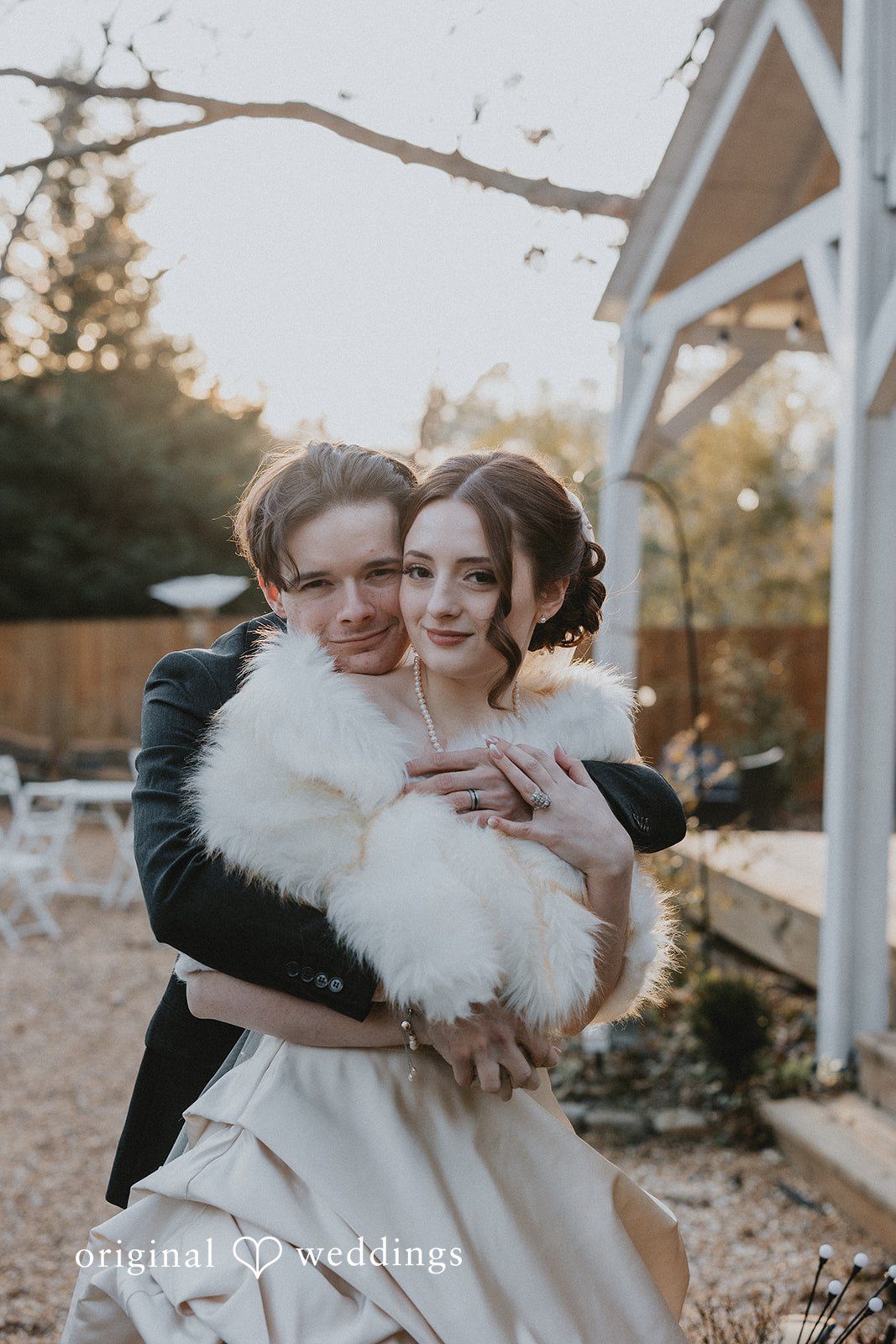 Ayana + Gabriel Groom embracing the bride from behind as she smiles wearing a fur shawl.