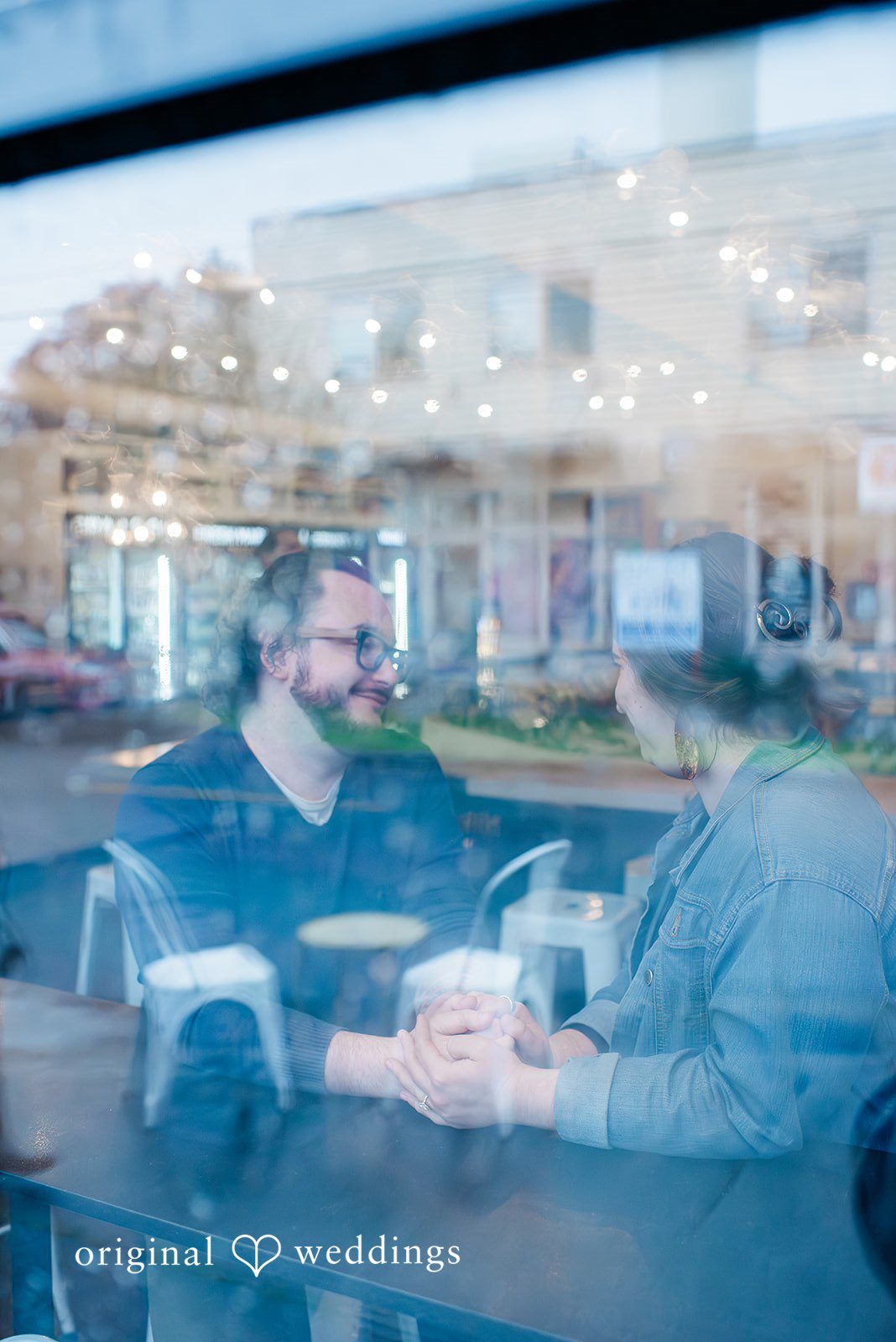 Intimate engagement portrait through the cafe window with warm lighting