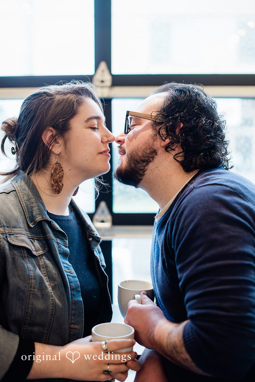 Couple sharing an intimate coffee shop kiss with natural window light