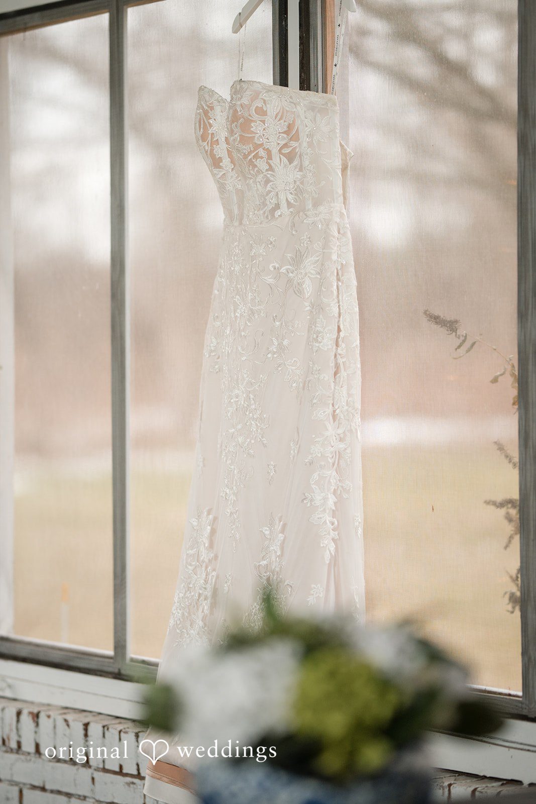 Logan + Bryan Elegant wedding dress hanging near window