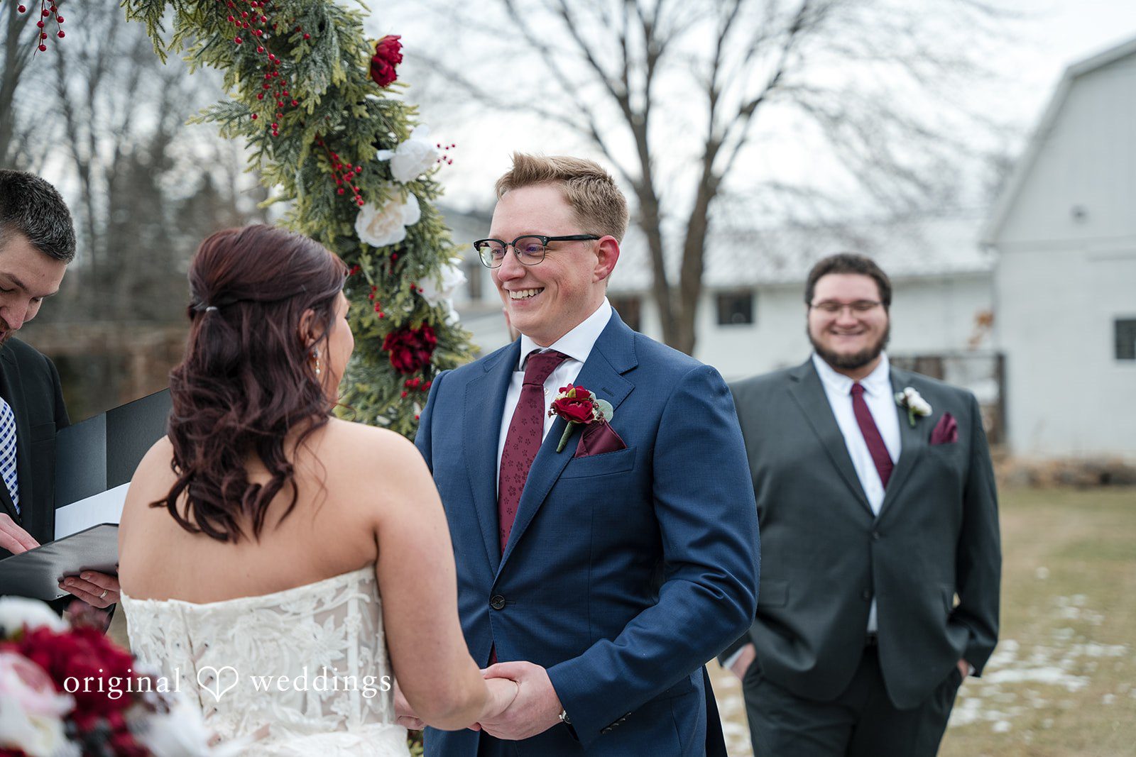 Logan + Bryan Groom smiling while holding hands with bride
