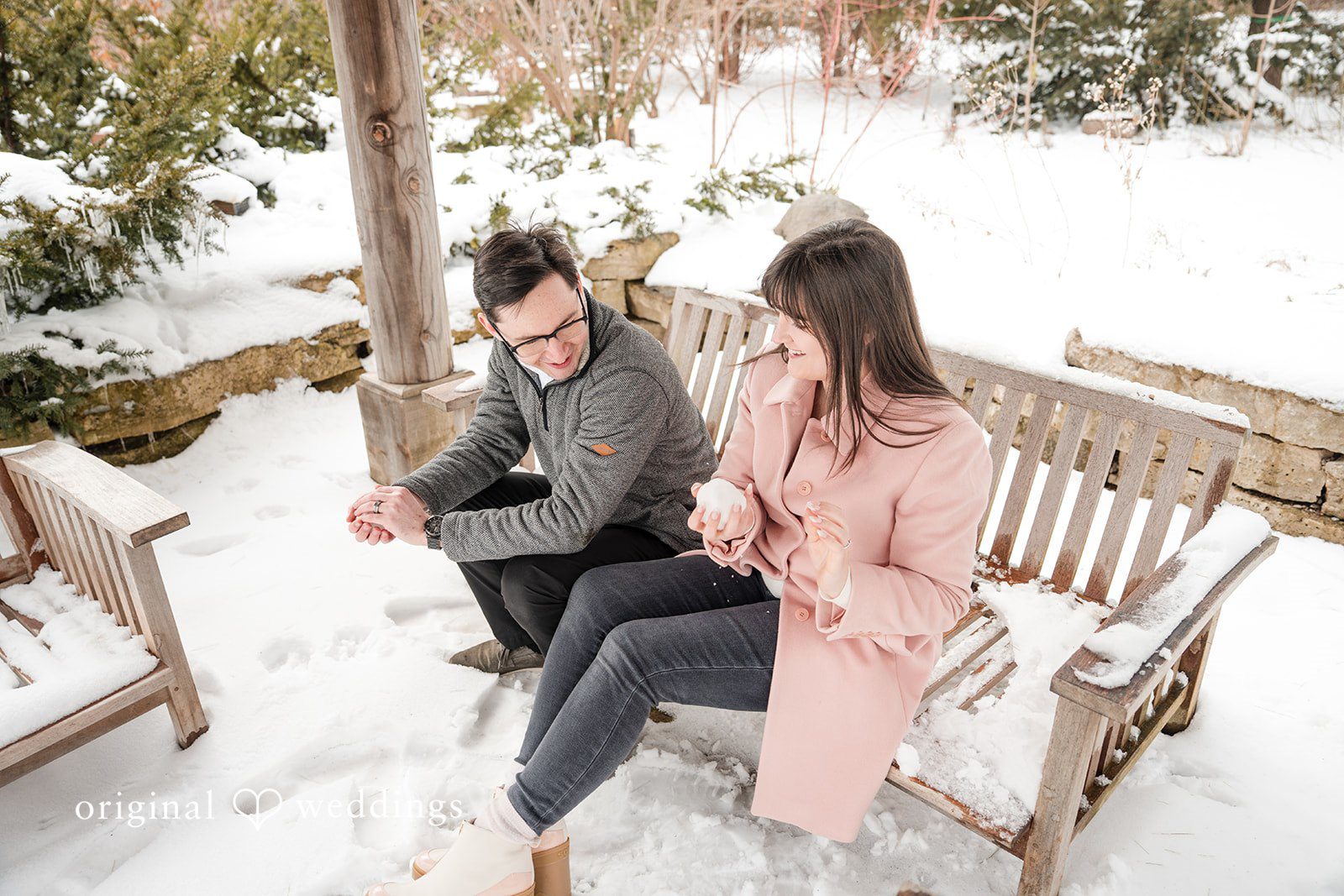 Couple sharing a joyful moment while laughing and playing with snow on a bench at Olbrich Gardens