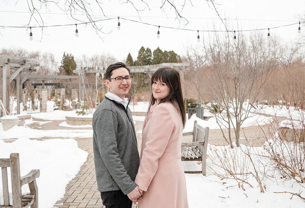 Engagement photography services by Original Weddings capturing a beautiful moment of the couple holding hands at Olbrich Gardens