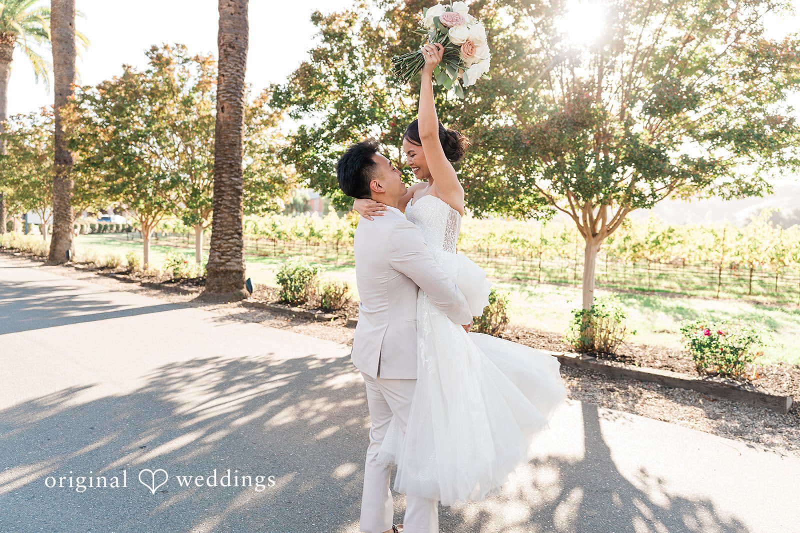 Charize Giann + Mark Shou Joyful bride and groom celebrating outdoors at Palm Event Center with bride holding her bouquet in the air captured by San Francisco wedding photographers from Original Weddings