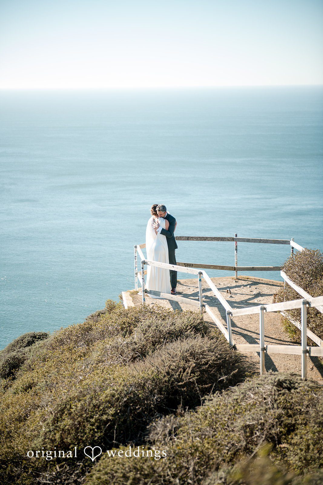The couple shares a hug by the ocean cliff