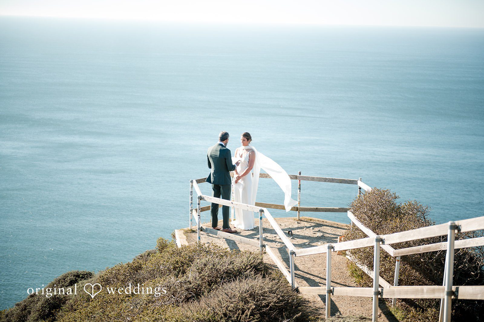 The couple shares a moment by the ocean cliff