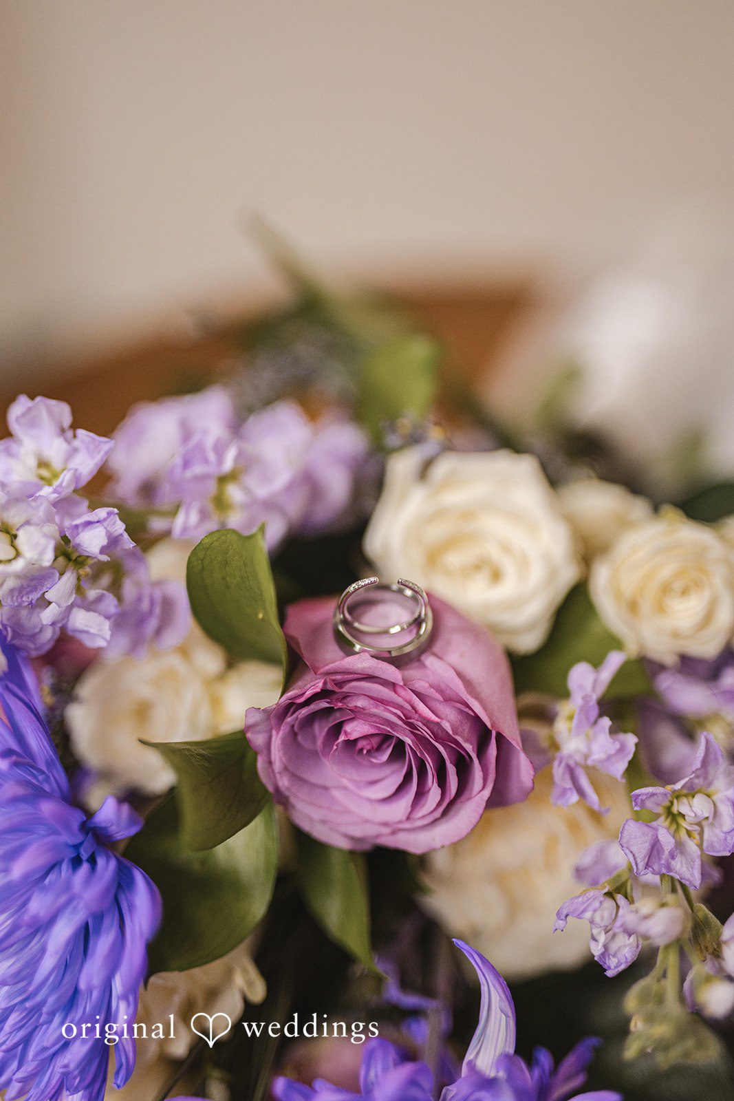 Samantha + Ryan Wedding ring resting on floral arrangement in close-up detail