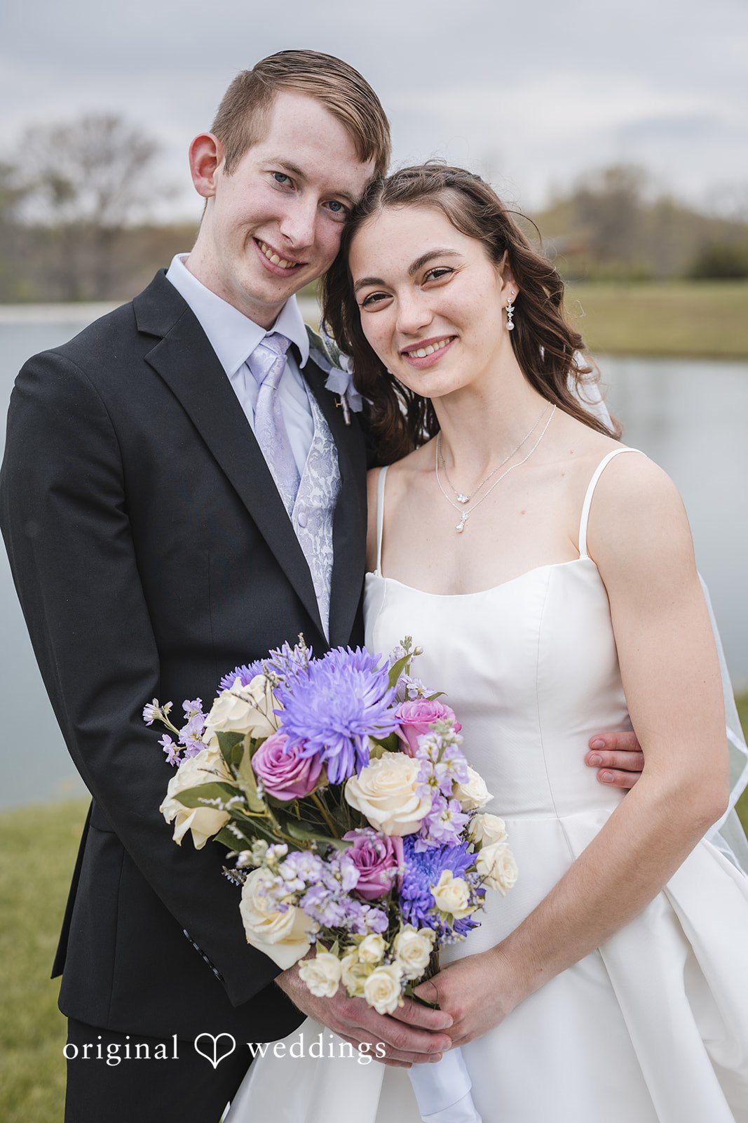 Samantha + Ryan Bride and groom posing together with a lake view behind them