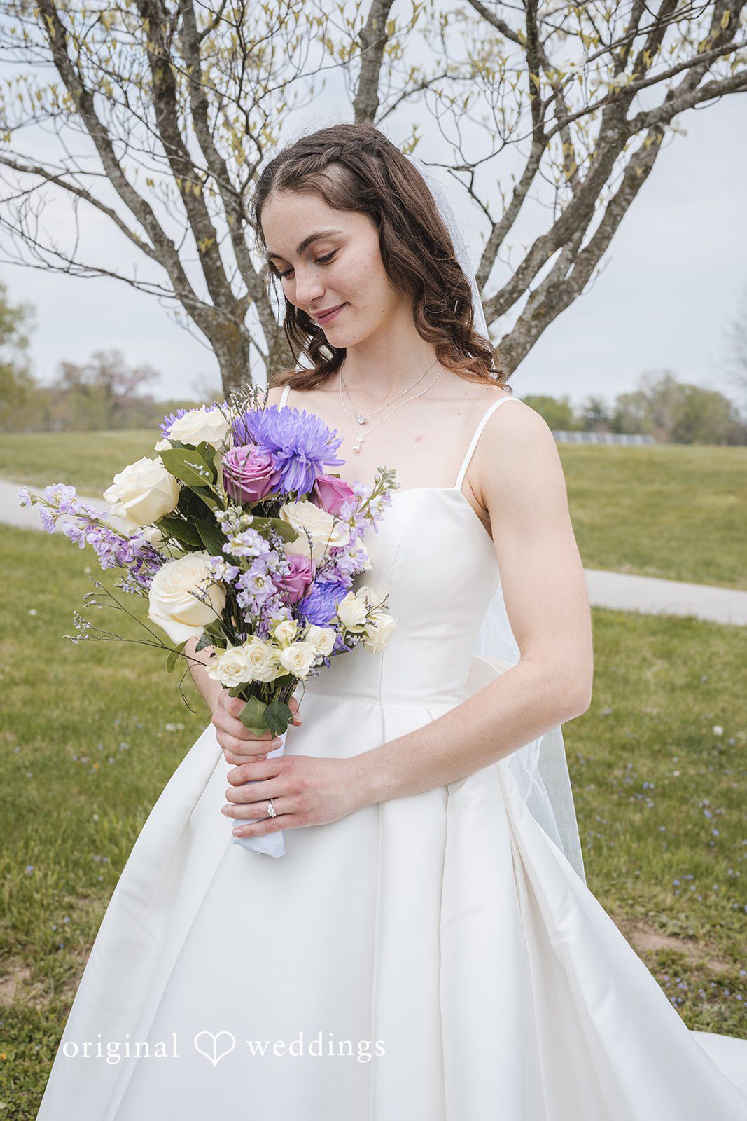 Samantha + Ryan Bride looking at her bouquet during outdoor portraits