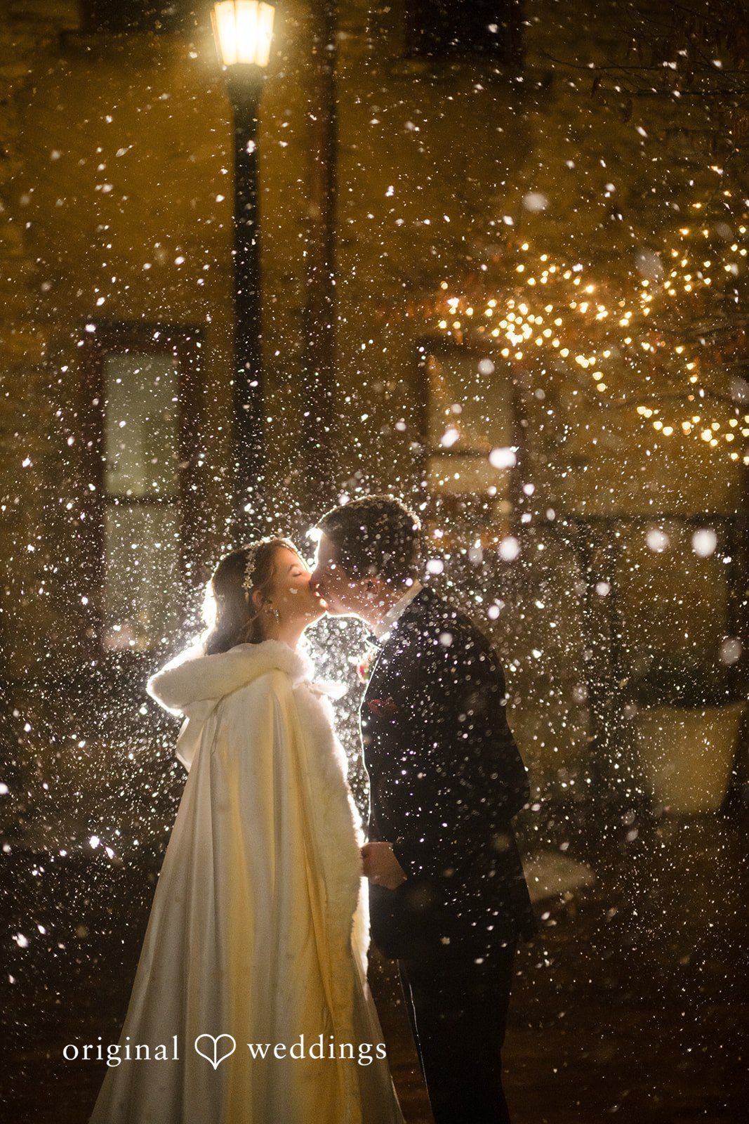 Bride and groom sharing a kiss in falling snow