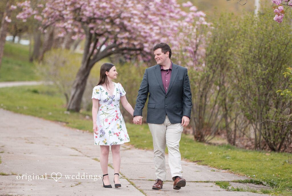 Erin + Nicholas Engagement Photography Services by Original Weddings capturing couple walking and looking at each other at Roger Williams Park