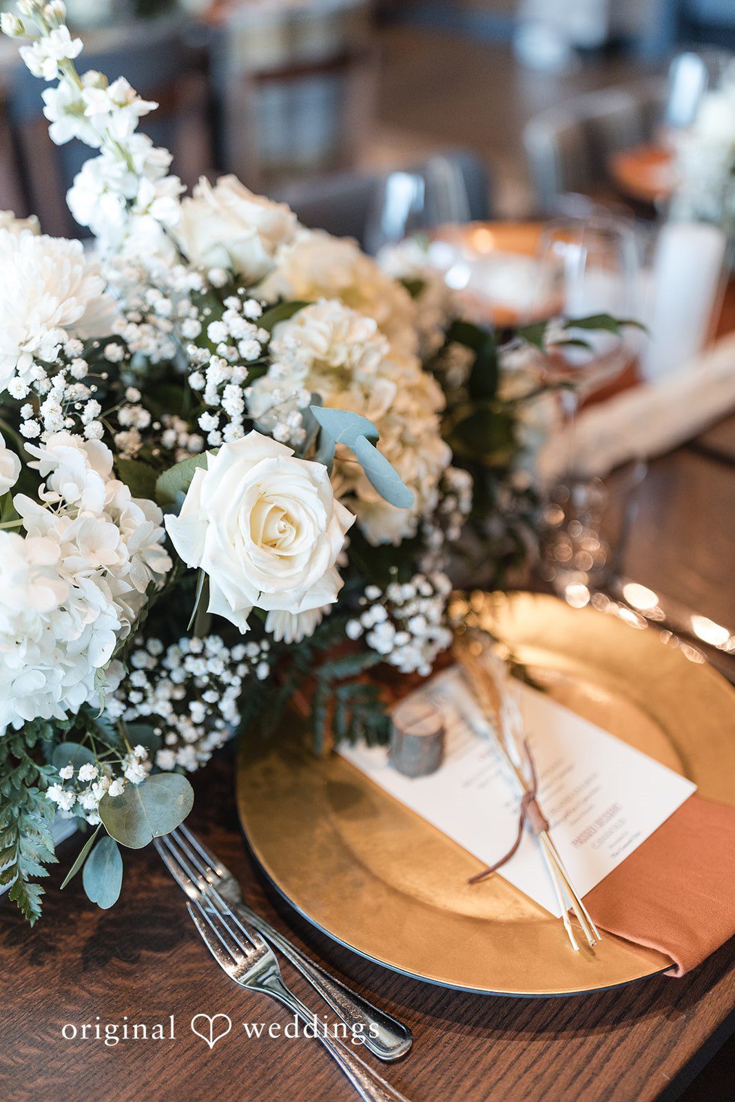 Beautiful reception table setup with flowers, plate and spoon detail