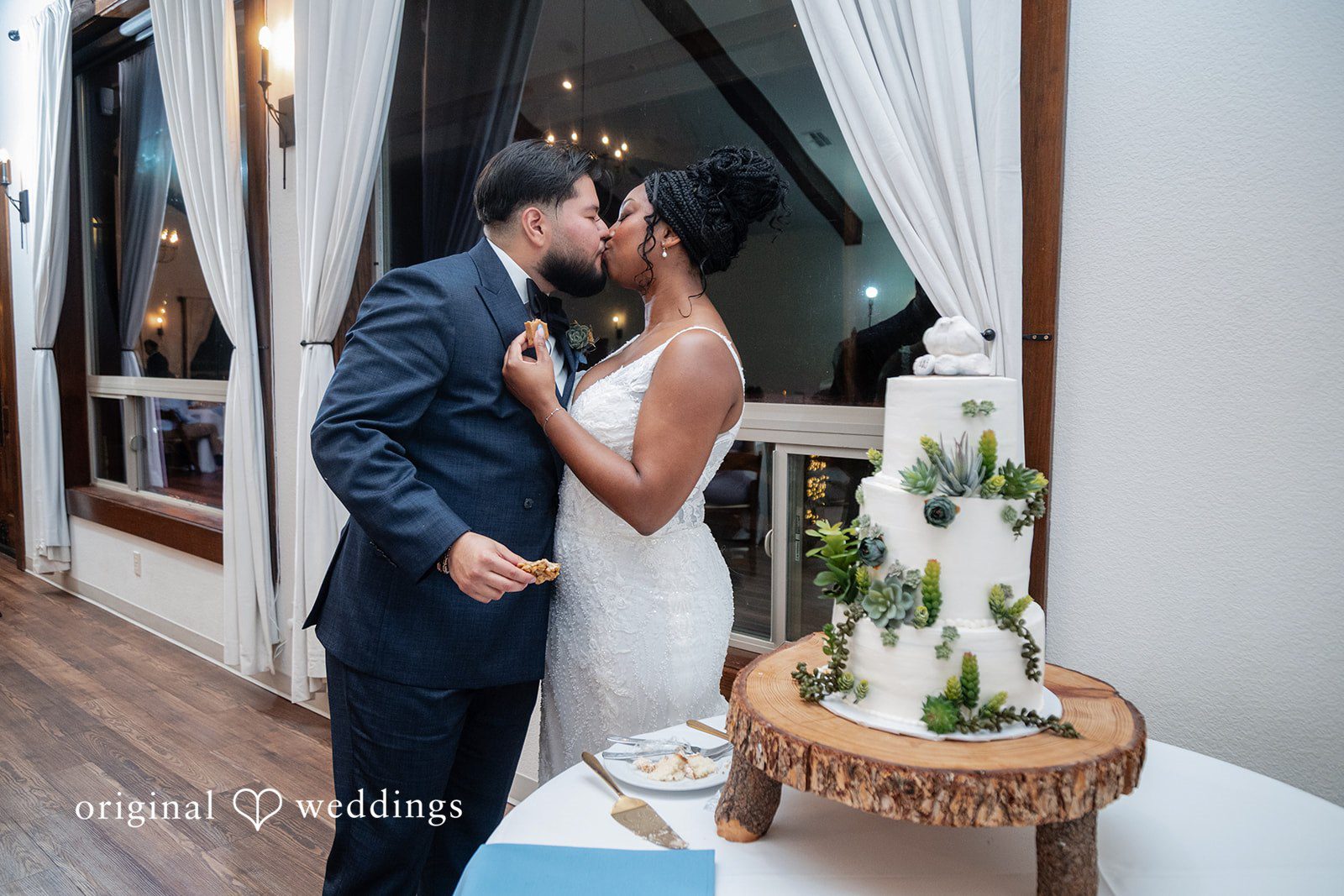 Couple sharing kiss after cutting wedding cake