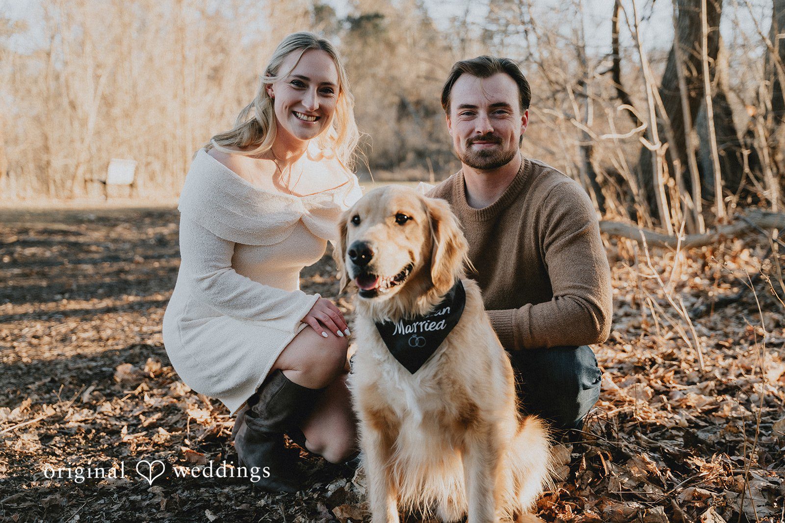 The couple sitting together in the woods with their golden retriever in the foreground.