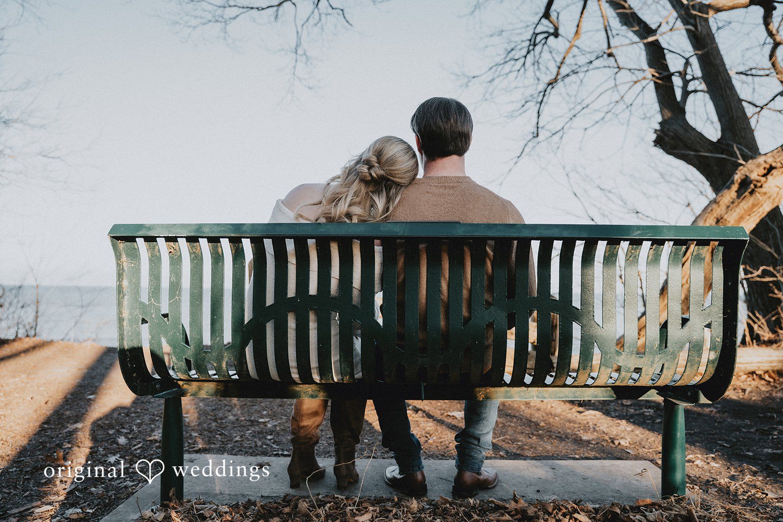 The couple seen from behind, sitting together on a curved wooden bench in Seven Bridges park.