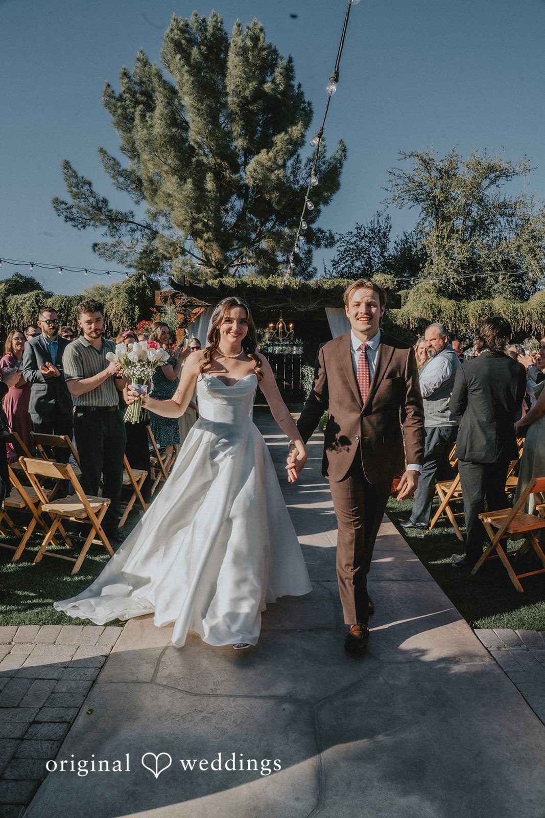 Bride and groom walking hand in hand down the outdoor wedding aisle after their ceremony