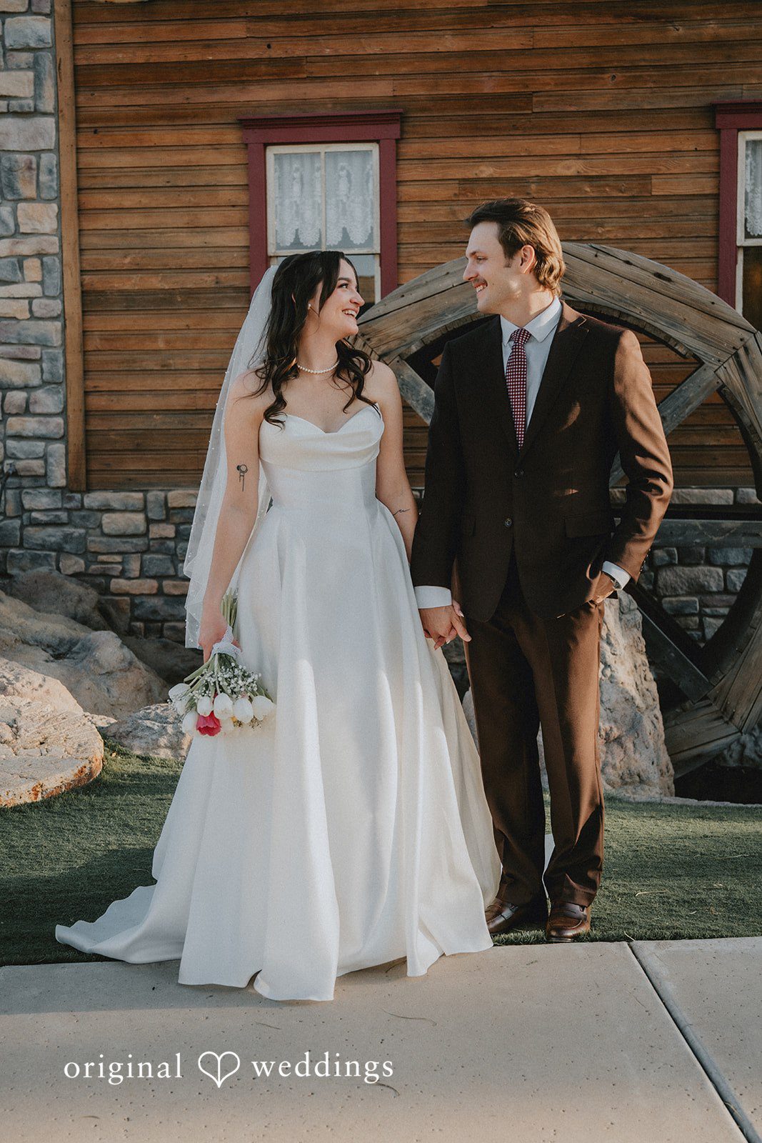 Bride and groom smiling at each other while holding hands