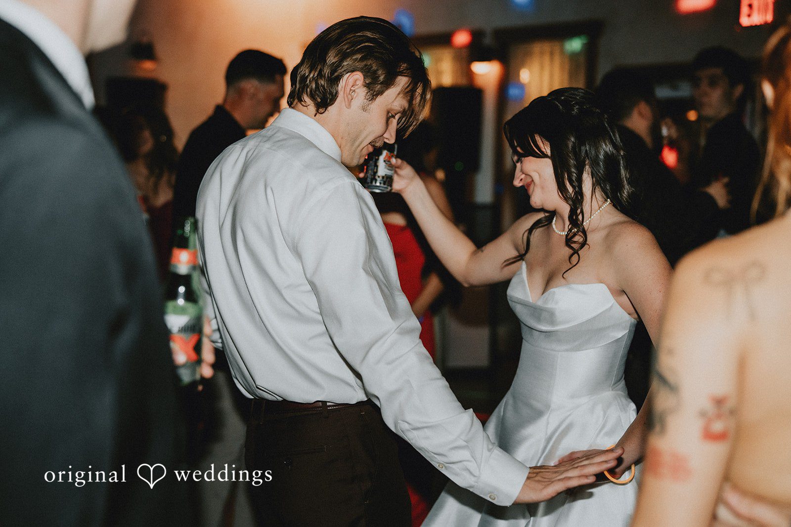 Newlywed couple smiling while dancing with guests
