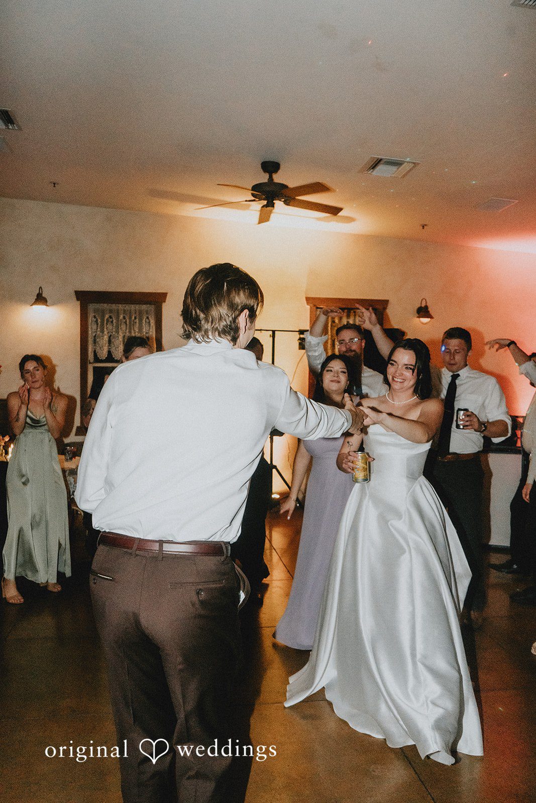 Bride and groom dancing together on the reception dance floor surrounded by wedding guests