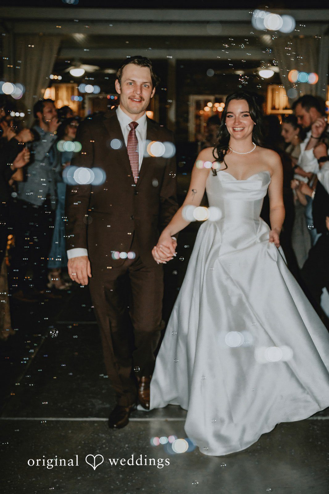 Bride and groom walking hand in hand through bubbles during their wedding reception at Shenandoah Mill